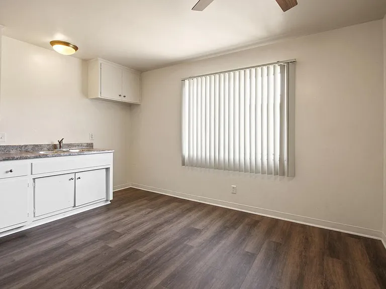 Dining area with ceiling fan, kitchen at the left, wood flooring throughout