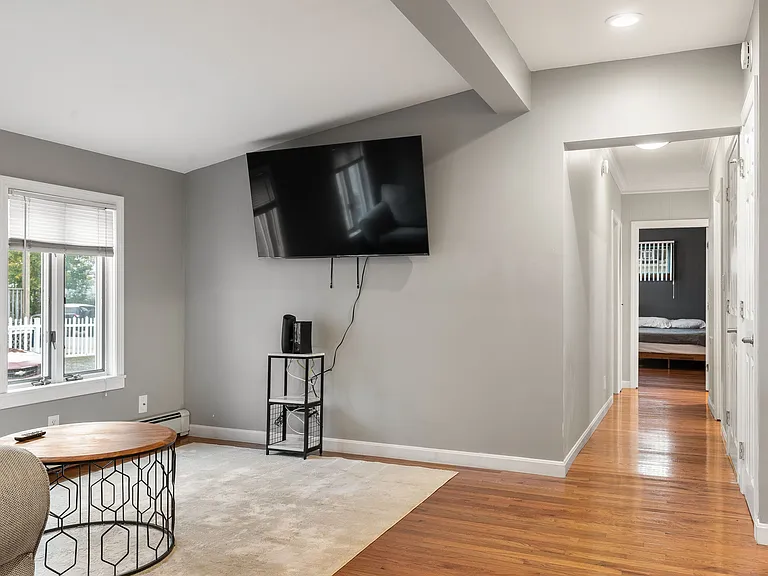 Open Floor Plan, Hardwood Flooring, Neutral Paint, Recessed Lighting, Wall-Mounted TV Area, View to Bedroom, Baseboard Heating.