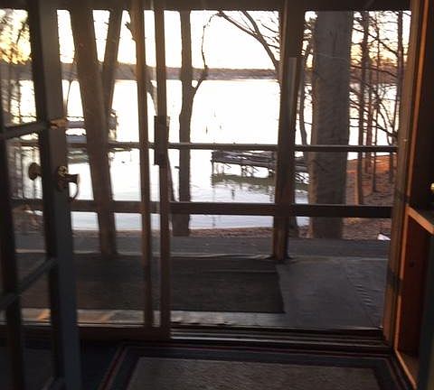 VIEW OF LAKE FROM INSIDE APT OUT FRENCH DOORS AND ACROSS ENCLOSED PORCH AND DECK.