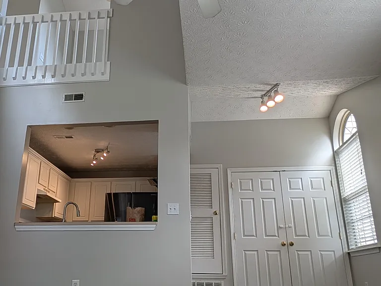 Dramatic high vaulted ceilings, ceiling fan, and open view looking into the kitchen