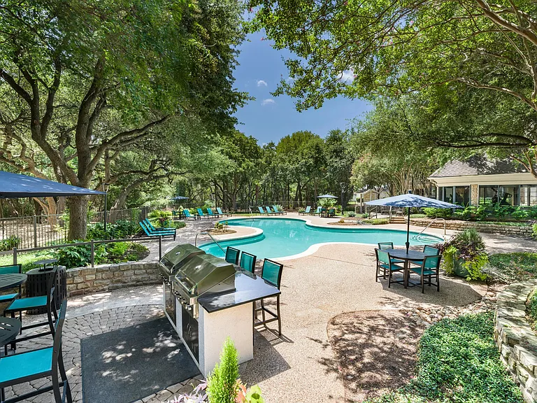 Surrounded by mature trees and seating areas, the poolside grilling station is ideal for outdoor dining and relaxing weekends.