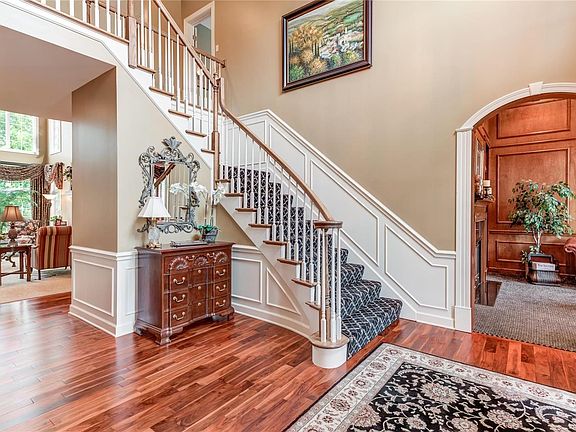 Impressive 2sty entrance hall that opens to great room, library and dining room with open staircase, charming arched doorways, detail crown molding/trim and gorgeous new Asian walnut wood floor in 2014
