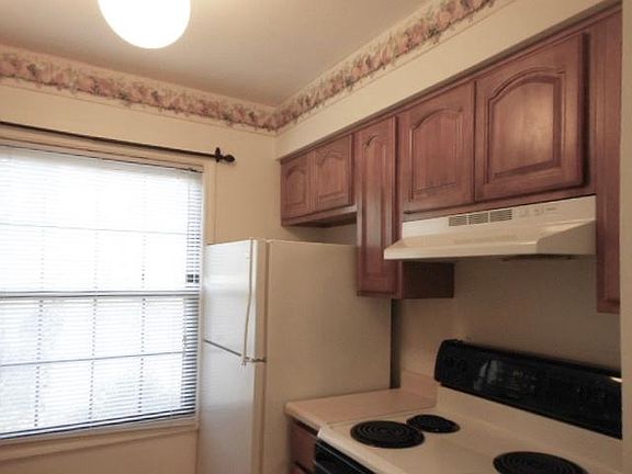 Right side of galley kitchen, equipped with refrigerator, electric stove and dishwasher.