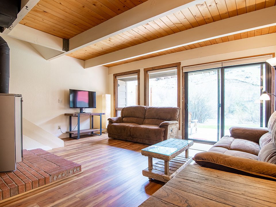 Bright & sunny, lots of natural light in living room with radiant natural gas stove & Lazy-boy reclining couches, direct access to private deck.