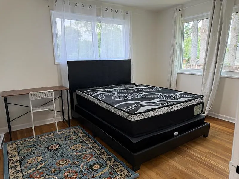 Private bedroom with a full bed, dedicated desk space, hardwood floors, and two windows with curtain panels for natural light - Valleywood Dr