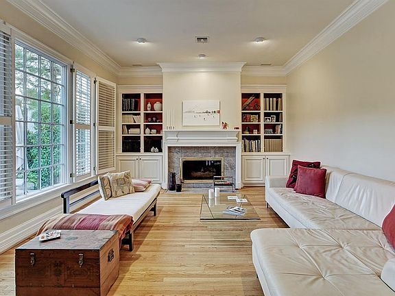 Large formal living room with charming fireplace and custom bookshelves. Large double pane windows provide an abundance of natural light which also offers a broad view of the unique courtyard.
