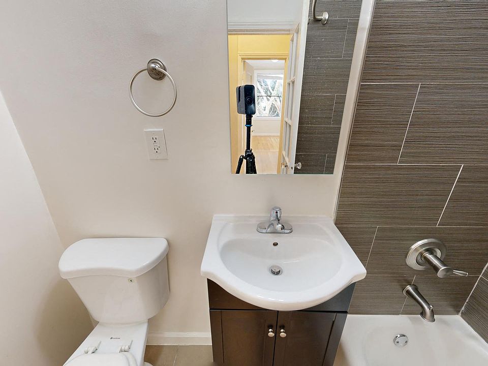 Bathroom with a toilet, sink, bathtub, and a mirror