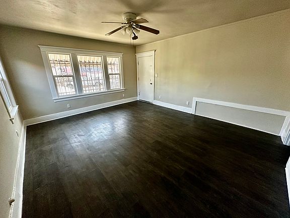Huge living room with lots of natural lights, windows, and ceiling fan.