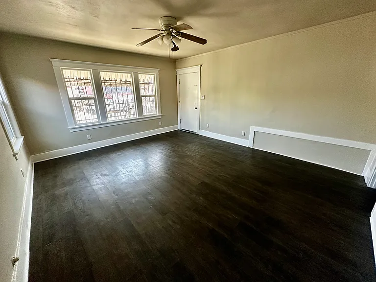 Huge living room with lots of natural lights, windows, and ceiling fan.