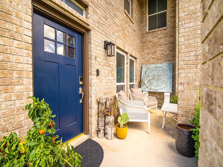 Welcome Home: A charming, private front porch welcomes you with a vibrant blue door, modern seating, and plenty of curb appeal. The perfect spot for your morning coffee!