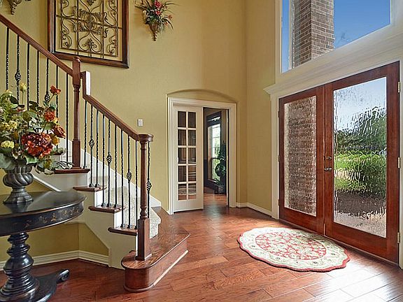 Stunning, double glass doors open to the Foyer that is finely appointed with wide plank wood floors, crown molding and an angular wrought iron staircase
