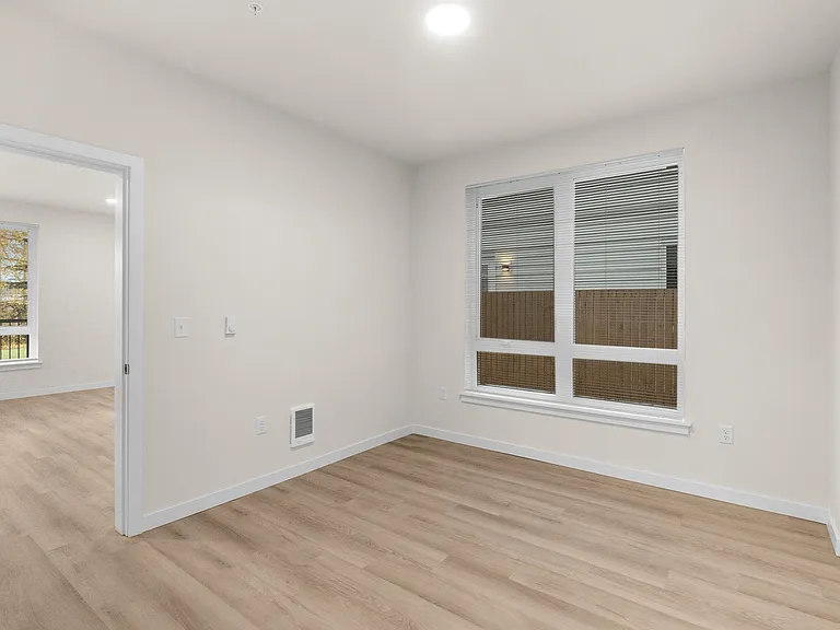 Bright apartment bedroom with wood-style floors, modern lighting, and window blinds. Bright apartment bedroom with wood-style floors, modern lighting, and window blinds.