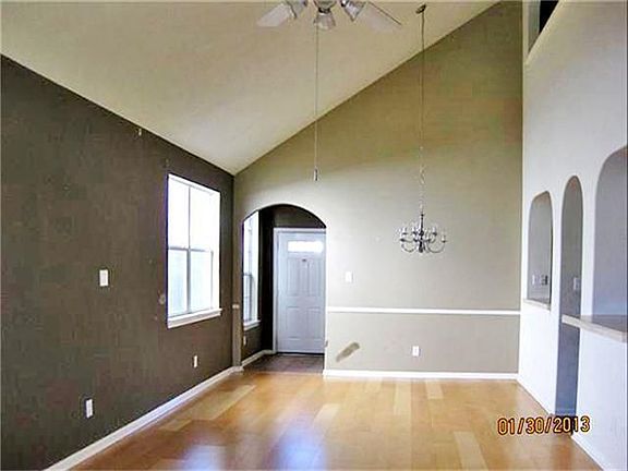 Soaring 2 story ceiling and laminate flooring view of dining area and front door.