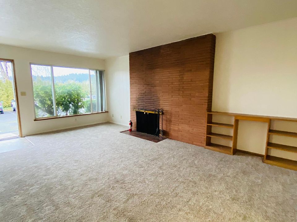 Living room with wood burning fireplace and huge window.