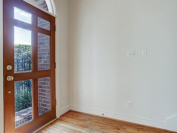 Lovely six glass panel wood front door and arched transom allows the natural light to filter in the entry.