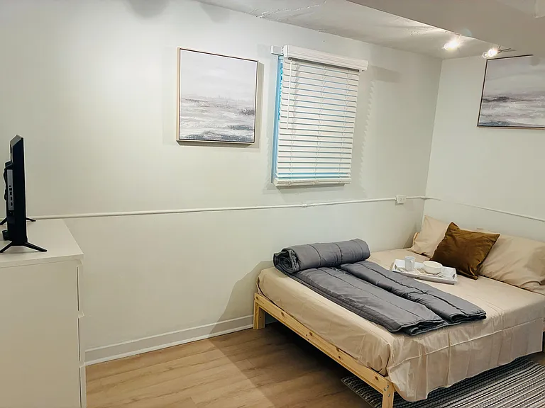 Neat bedroom with a comfortable bed, dresser, and window with blinds for privacy and natural light.