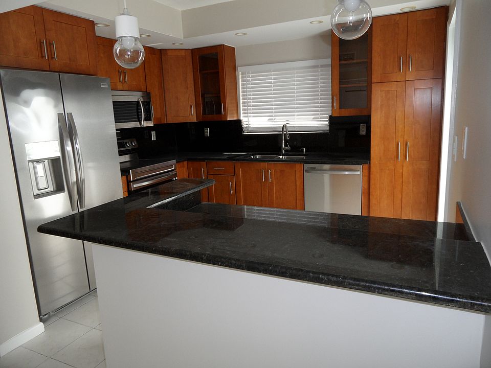 Open, roomy kitchen with wood cabinetry, granite counters and stainless appliances.