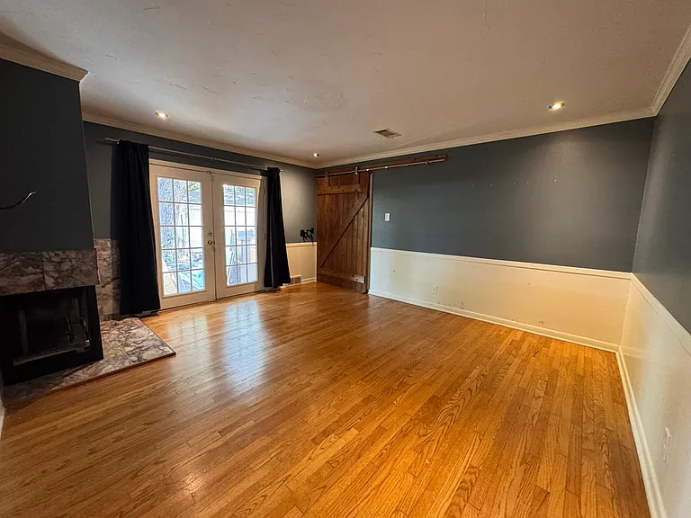 Filled with natural light from beautiful French doors. This versatile room boasts a rustic barn door accent and original hardwood flooring. Currently being upgraded with a new built-in closet, making it a perfect bedroom or dedicated office space.