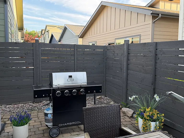 The outdoor patio is perfect for entertaining, featuring a large dining table with umbrella shade and a gas grill for easy outdoor cooking and dining.