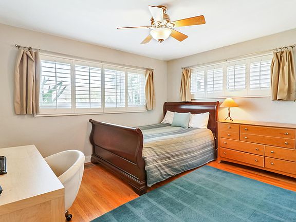 Second bedroom is roomy and bright and includes a large closet with a supplemental shelving area and custom-made wood shutters (queen bed pictured in photo).