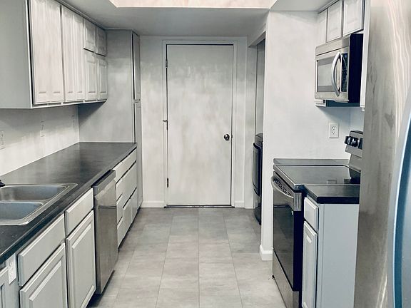 Galley kitchen (with new appliances including washer and dryer) connected to garage, dining room and back patio.