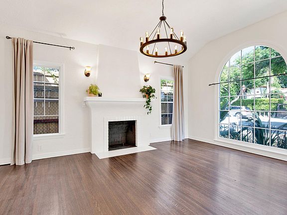 Living room features vaulted ceiling and large picture window with decorative fireplace.