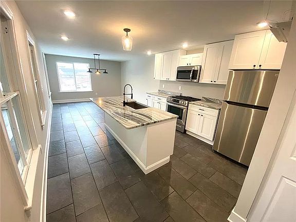 Brand new, sun-drenched kitchen with farm house sink, stainless steel appliances, granite countertops, slate floor.