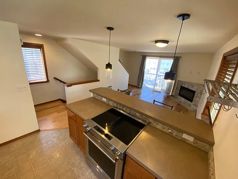 2nd Floor _ Open-concept living area featuring sleek hardwood flooring, a cozy tiled fireplace, a kitchen with stainless steel appliances and a premium slide-in electric range, plus a convenient half bathroom.