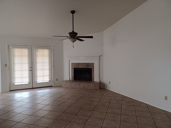 Family room with stylish ceiling fan, fireplace, French doors to covered patio, open concept off the kitchen