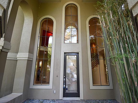 A custom leaded art glass front door welcomes you amid serene bamboo in the recessed entry.