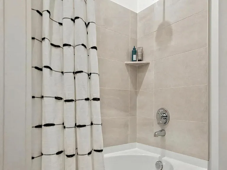 Shower and Bathtub Combo with Beige Wall Tiles and Storage Shelf