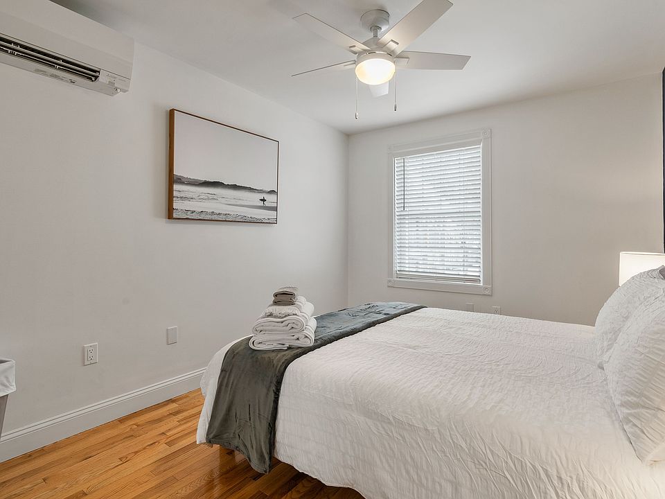 Bedroom, Hardwood Floors, Ceiling Fan, Mini-Split AC, Queen Bed, Natural Light, White Walls, Modern Decor.