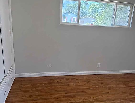 Bright interior room with refinished hardwood floors, fresh paint, and natural light.