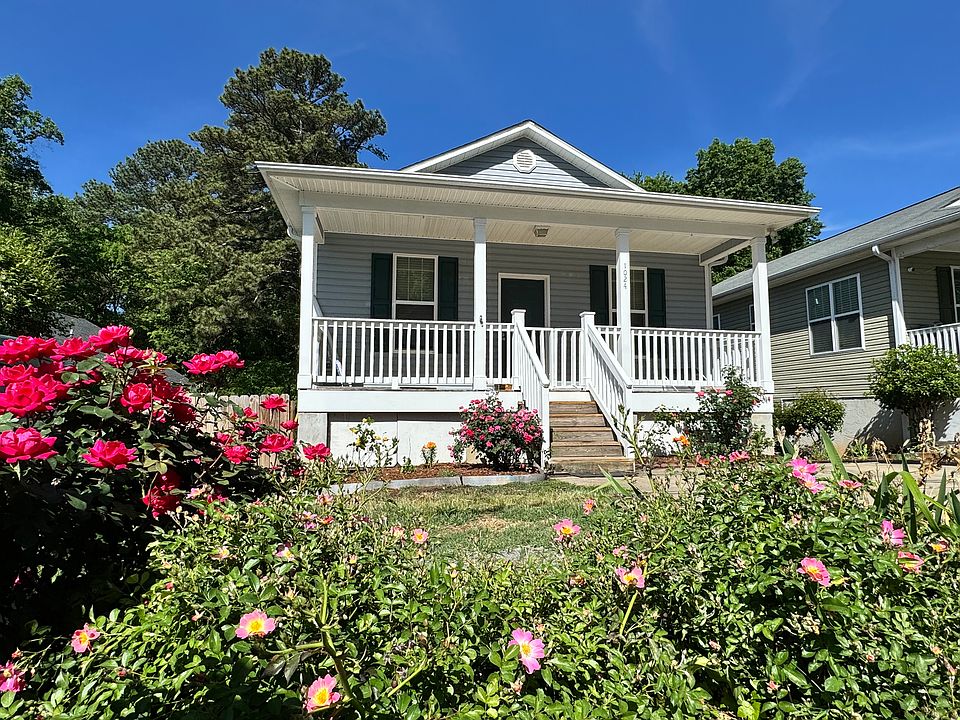 Welcome! The front porch is framed with blooming flower beds and lush landscaping. The porch is fully enclosed with white wooden fencing and a gate, making it a safe, comfortable spot for kids and pets.