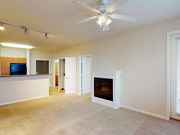 Apartment kitchen, dining and living room with plush carpet flooring.