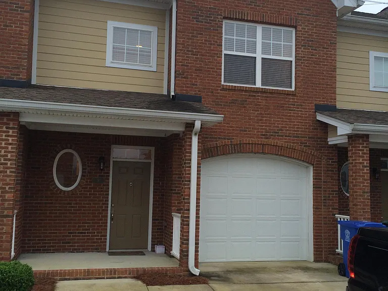 Front view of townhouse situated within gated community. Front porch and one car garage. Exterior of complex has been painted since this photo was taken.