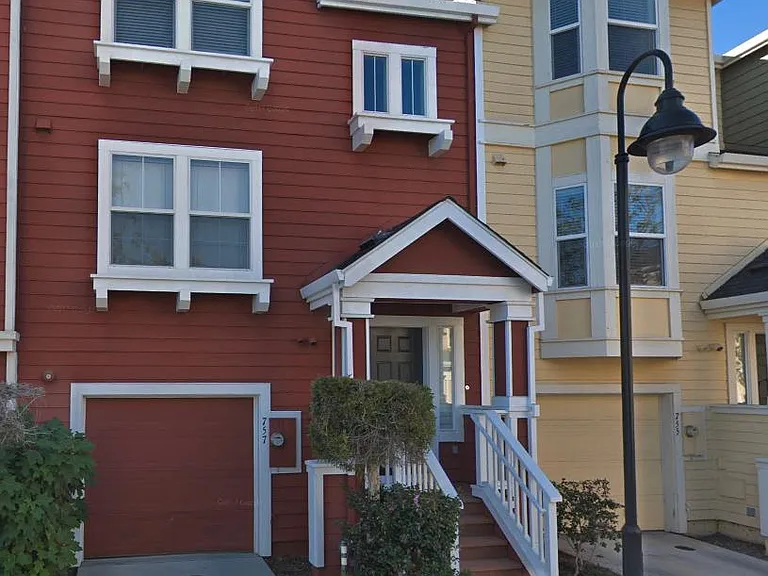 Tri-level townhouse with a small front porch and a backyard.