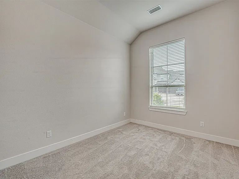 Bedroom featuring a vaulted ceiling and window with horizontal blinds