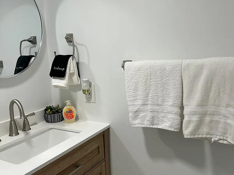 Cozy bathroom with towel racks, soap, towels, and mirror.