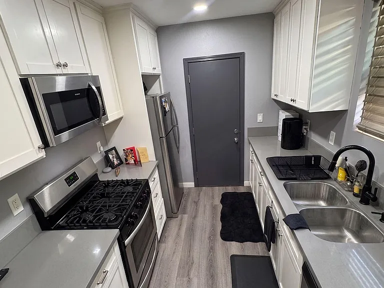 Galley kitchen with shaker cabinets, ample counter space, stainless appliances, and double-basin sink for easy meal prep.