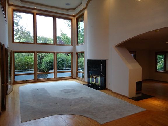 Formal living room with fireplace, dramatic ceilings & a wall of windows