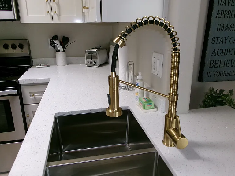 New gold modern kitchen faucet on the new quartz counters.