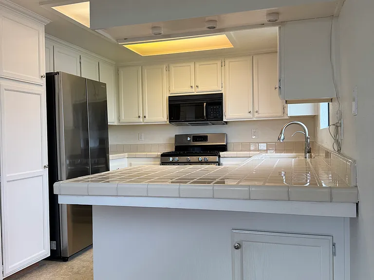 View of Breakfast/Serving Counter into Kitchen with New Counter Depth Fridge. 5 Burner Range, Microwave, Dishwasher, and Reverse Osmosis Water Purification System on Tap