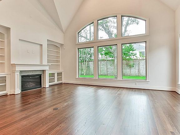 Family room complemented by vaulted ceiling, walls of windows and built ins surrounding fireplace.