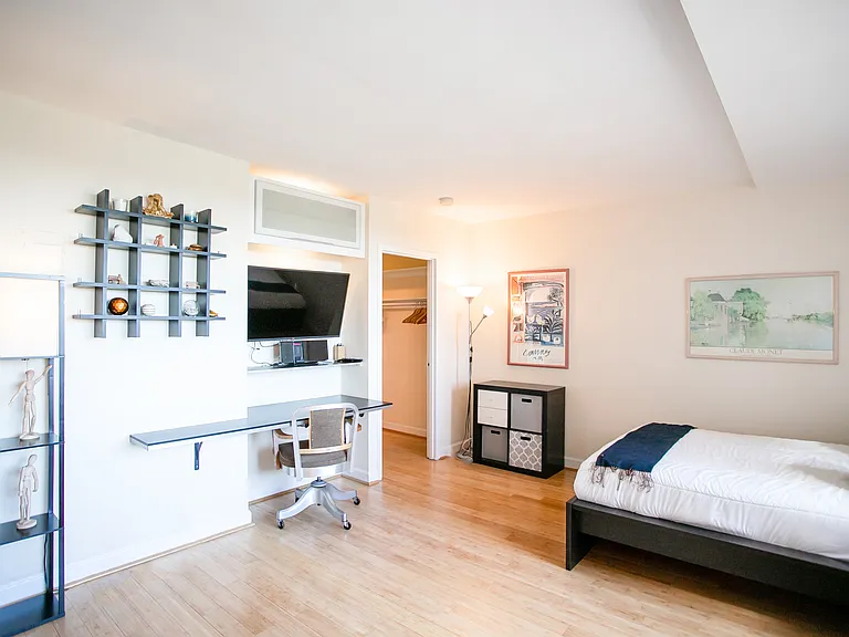 A spacious studio with built-in desk, media cabinet, and task lighting.
