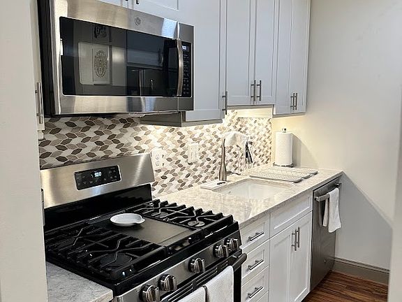 Complete renovated custom soft-close cabinets, white ceramic sink, surrounded by luxurious white quartz.