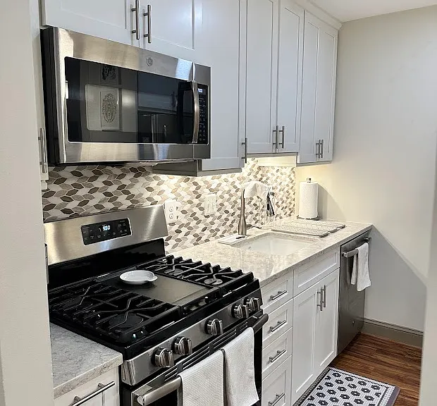 Complete renovated custom soft-close cabinets, white ceramic sink, surrounded by luxurious white quartz.