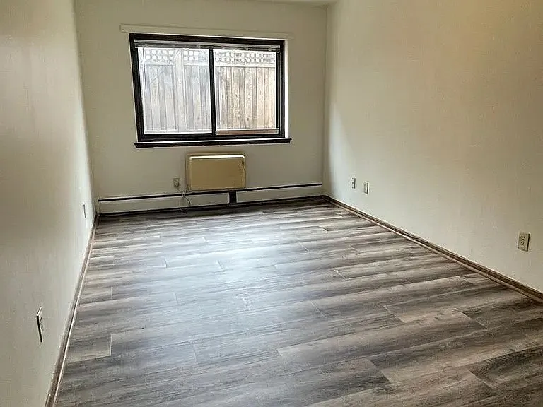 Step into a spacious, light-filled living area at LS Capital Group, featuring modern flooring and large windows that create an inviting atmosphere. Perfect for personalizing your space, this is your chance to find your new home. Schedule a visit today!
