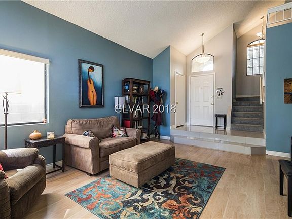Living room looking towards front door and stairwell. Wood laminate floors , newer tile & gray carpet play well off colors.