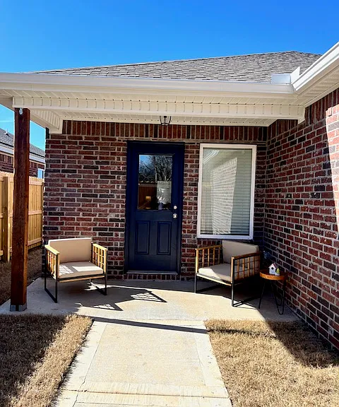 Covered back porch inside small fenced backyard.
